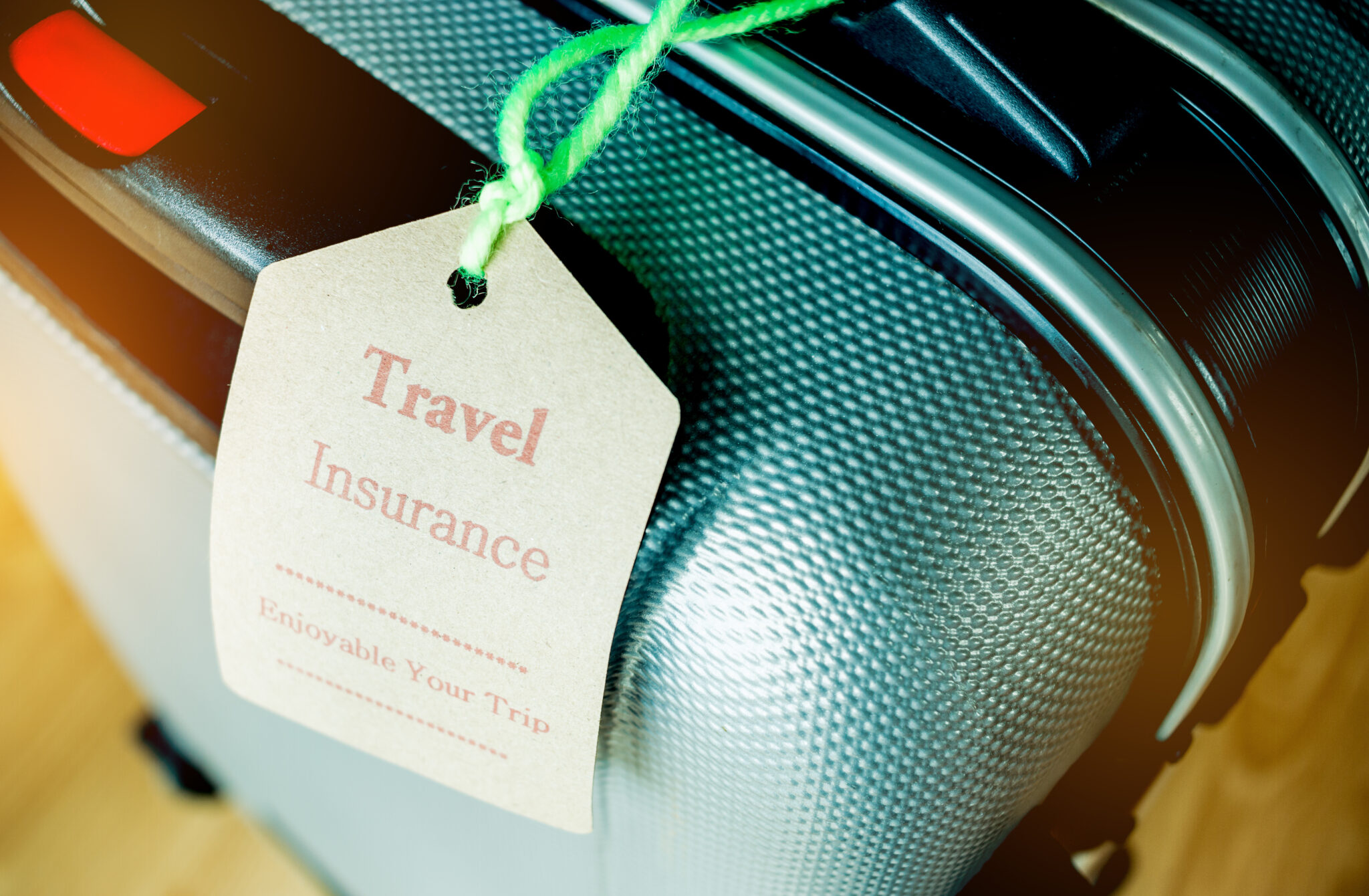 Travel Insurance tag on Suitcase safety with letters enjoyable your trip on bag light blurred background, that is intended cover medical expenses, trip cancellation or flight accident.